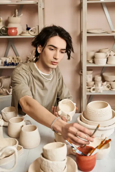 Creative individual engaged in crafting pottery amidst an inspiring studio filled with artwork. — Stock Photo