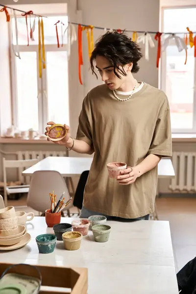 Handsome man engages with colorful pottery in a bright and inspiring studio environment. — Stock Photo