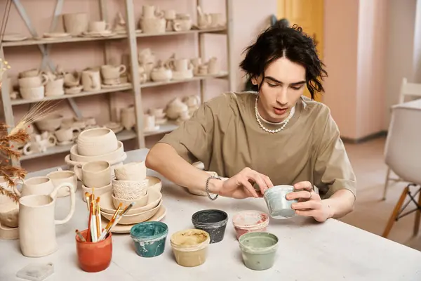 A handsome man creates pottery, mixing colors in a bright, inspiring studio. — Stock Photo