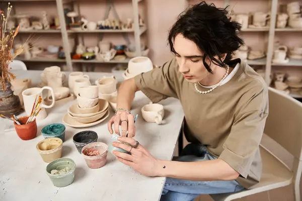 Stylish man carefully shapes clay in a bright and inviting pottery studio filled with art. — Stock Photo
