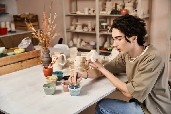 Un hombre con estilo se dedica al arte de la cerámica, la elaboración de piezas únicas en un estudio creativo. - foto de stock