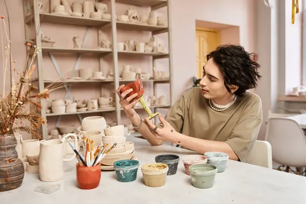 A handsome man explores his artistic side in a pottery studio, showcasing beautiful ceramics. — Stock Photo