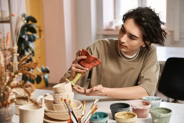 A handsome man explores pottery in a bright, inspiring ceramics studio. — Stock Photo