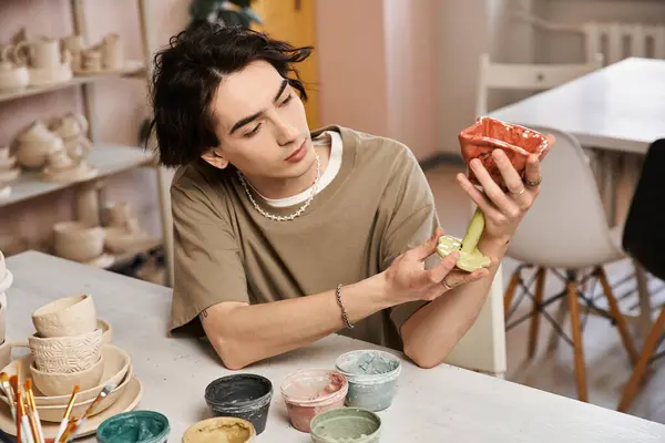 A handsome man immerses himself in pottery artistry, skillfully molding colorful clay creations. — Stock Photo