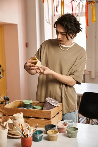 Hombre guapo explora su creatividad en un estudio de cerámica rodeado de piezas de cerámica de colores. - foto de stock