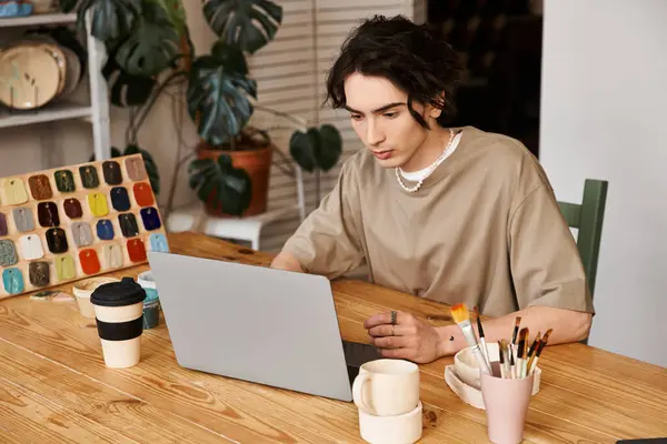Hombre con estilo centrado en los diseños de cerámica mientras está rodeado de materiales creativos en su estudio. - foto de stock