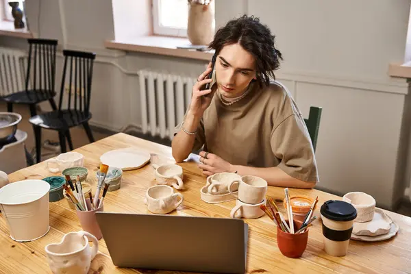 Bello uomo immerso nel suo studio di ceramica, la lavorazione della ceramica e la gestione di una conversazione telefonica. — Foto stock