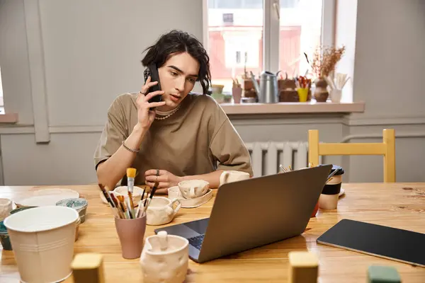 Stylish man explores his artistic side in a pottery studio as he chats on the phone. — Stock Photo