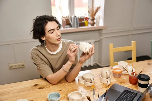 A stylish man skillfully shapes pottery while surrounded by tools and materials in a bright studio. — Stock Photo