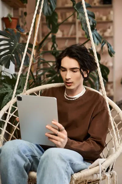 Stylish man engages with digital pottery resources in a creative studio filled with plants. — Stock Photo