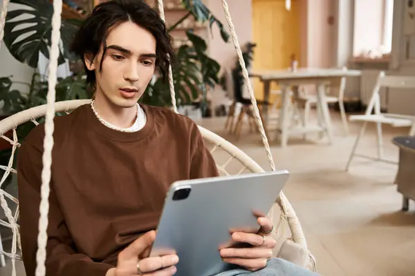 A stylish man explores pottery techniques on a tablet in a lively studio. — Stock Photo
