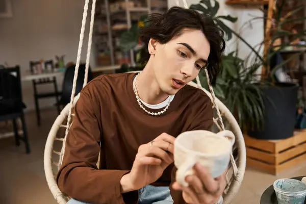 A handsome man passionately shapes ceramics in a vibrant pottery studio, surrounded by art. — Stock Photo