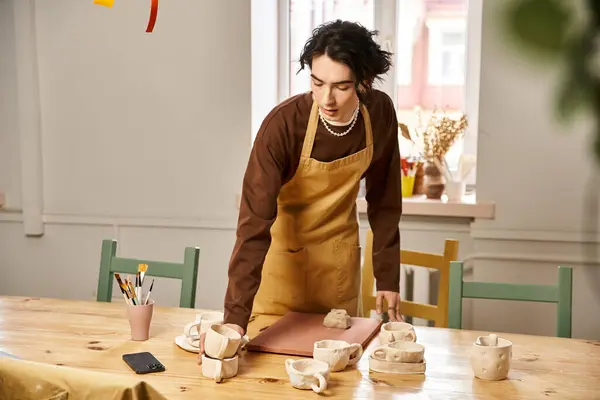 Handsome man engages in the art of pottery, shaping clay amidst a vibrant studio atmosphere. — Stock Photo
