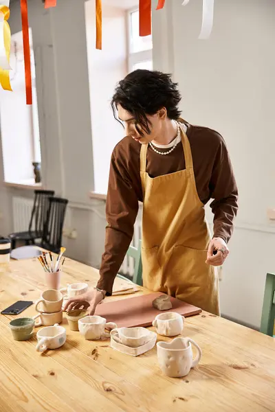 A talented man focuses on shaping clay amidst colorful decor in a bustling pottery studio. — Stock Photo