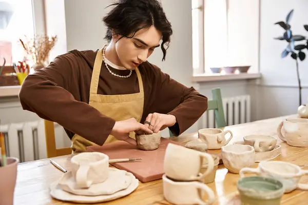 A handsome man is focused on shaping clay, surrounded by beautiful ceramic creations in the studio. — Stock Photo