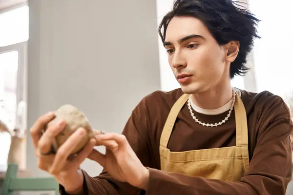 Hombre con estilo centrado en dar forma a la arcilla en un estudio de cerámica lleno de inspiración y creatividad. - foto de stock