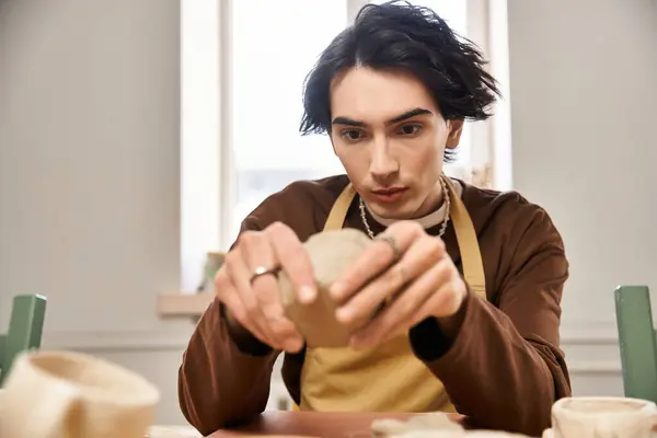In a pottery studio, a man focuses intensely on crafting a handmade ceramic piece with passion. — Stock Photo