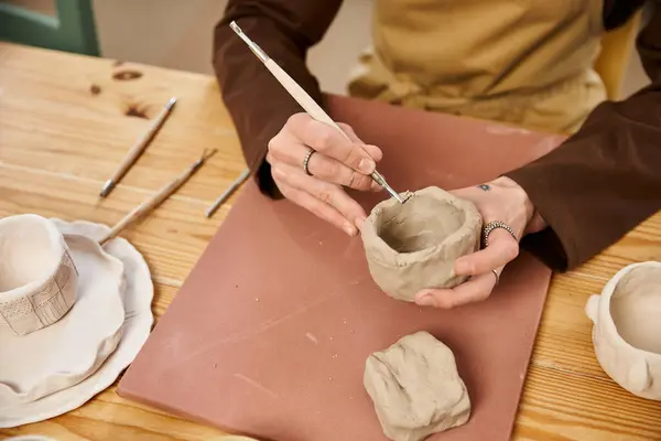 Hombre guapo expresa la creatividad mediante la conformación de la arcilla y la adición de detalles intrincados en un estudio de cerámica. - foto de stock