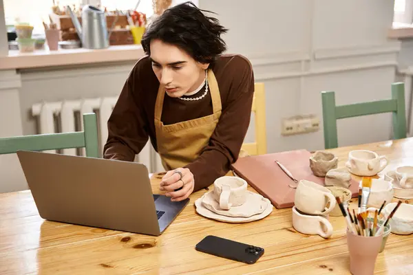 A handsome man blends technology and artistry while creating pottery in his studio. — Stock Photo