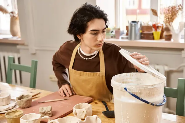 Hombre guapo se dedica al arte de la cerámica, la creación de piezas de cerámica en un estudio vibrante. - foto de stock
