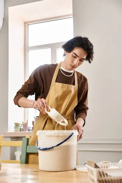 A handsome man is focused on crafting pottery in a bright studio, surrounded by creative tools. — Stock Photo