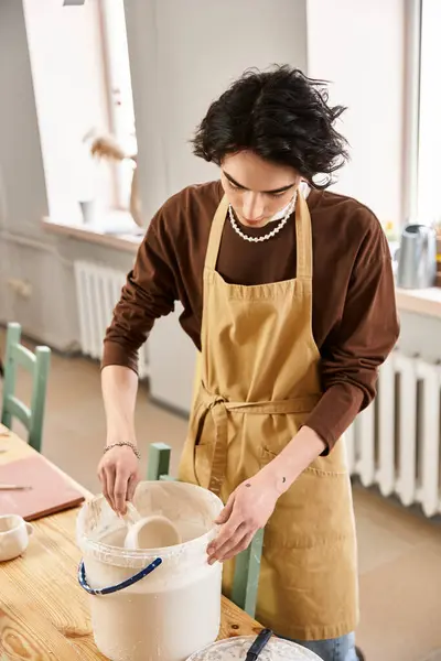 A fashionable man passionately works with clay in a sunny pottery studio, expressing creativity. — Stock Photo