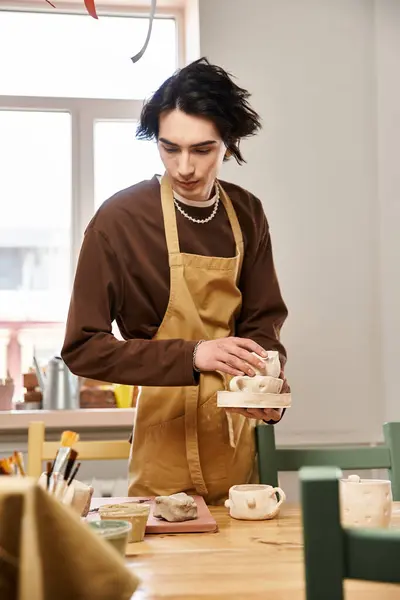 A fashionable man skillfully shapes pottery in a sunny studio dedicated to artistic expression. — Stock Photo