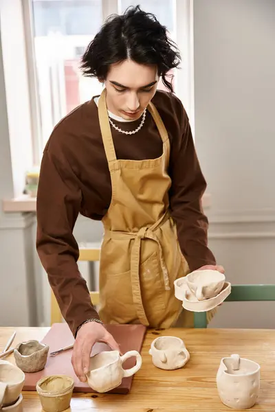 A skilled man in an apron focuses on shaping pottery while surrounded by artistic materials. — Stock Photo