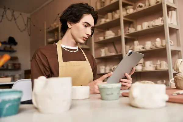 In a pottery studio, a handsome man learns ceramics amid unique creations. — Stock Photo