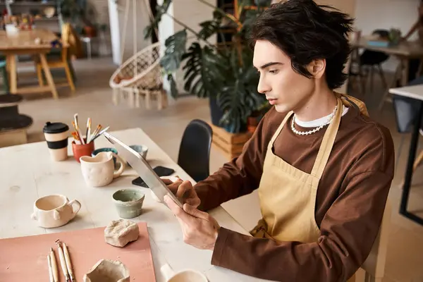 Handsome man engages in creative pottery projects surrounded by artisanal tools and decor. — Stock Photo