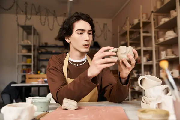 A skilled man shapes clay in a pottery studio filled with art tools and creations. — Stock Photo