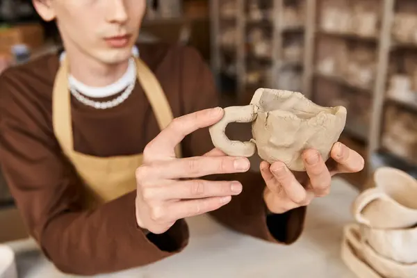 Un hombre forma una taza de barro en un vibrante y creativo estudio de cerámica. - foto de stock