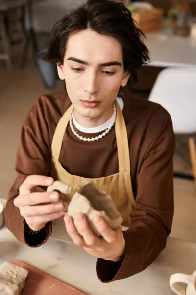 A young man skillfully works with clay in a pottery studio, showcasing his artistic talent. — Stock Photo