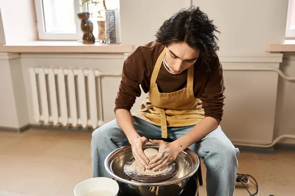 El hombre con estilo moldea hábilmente la arcilla en su estudio de cerámica, encarnando la creatividad y la pasión artística. - foto de stock