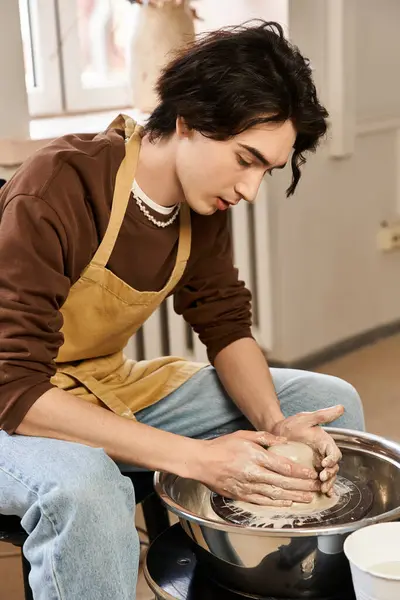 Hombre artístico hábilmente moldeando arcilla en una rueda de cerámica con creatividad en un estudio brillante. - foto de stock