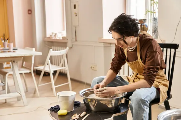 Un hombre guapo forma hábilmente la arcilla en una rueda de cerámica en un estudio brillante e inspirador. - foto de stock