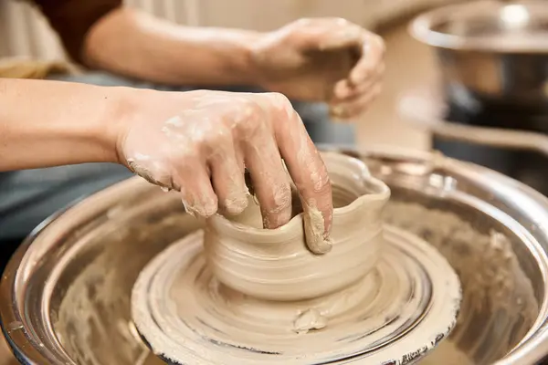 A talented man skillfully shapes clay into a beautiful pottery piece while surrounded by creativity. — Stock Photo