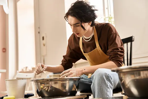 El hombre moldea hábilmente la arcilla mientras está rodeado de diversas herramientas de cerámica y decoración creativa. - foto de stock