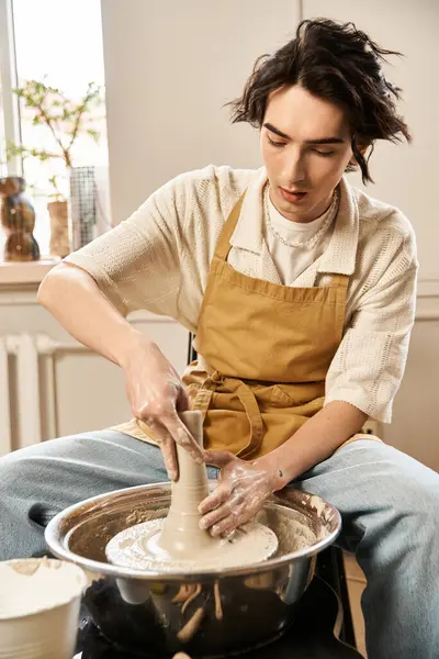 Hombre guapo hábilmente moldea arcilla en una rueda de alfarero en un estudio de cerámica brillante e inspirador. - foto de stock
