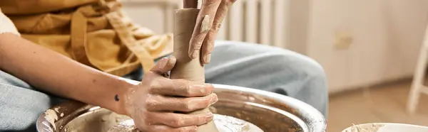 A handsome man skillfully molds a piece of clay in a vibrant pottery studio filled with creativity. — Stock Photo