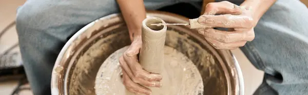 Un hombre guapo forma hábilmente arcilla húmeda en una rueda de cerámica, mostrando su creatividad. - foto de stock