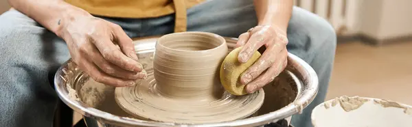 Hombre guapo hábilmente moldea la arcilla en una rueda de cerámica, mostrando arte y artesanía. - foto de stock