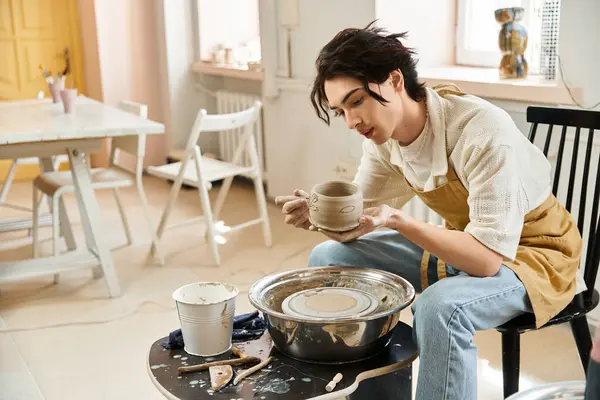 A fashionable man engages in pottery, shaping clay at his creative workspace filled with light. — Stock Photo