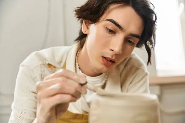 A dedicated and fashionable man meticulously painting unique pottery creations in his studio. — Stock Photo