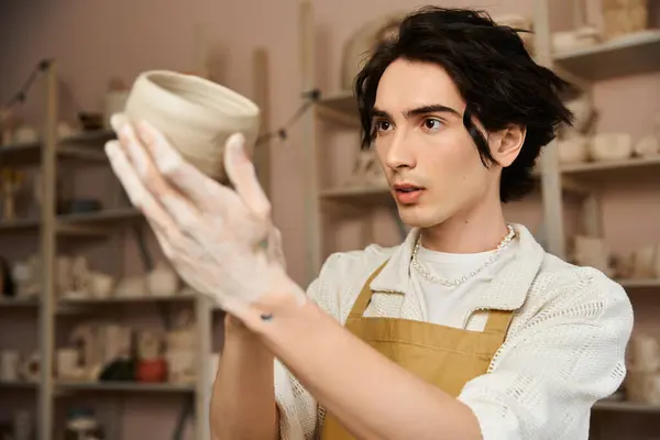 Un hombre de moda forma hábilmente la arcilla mientras está inmerso en su estudio de cerámica, mostrando arte. - foto de stock