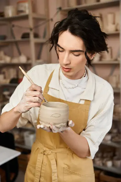 Handsome man focuses on shaping clay, showcasing talent in a lively pottery studio atmosphere. — Stock Photo
