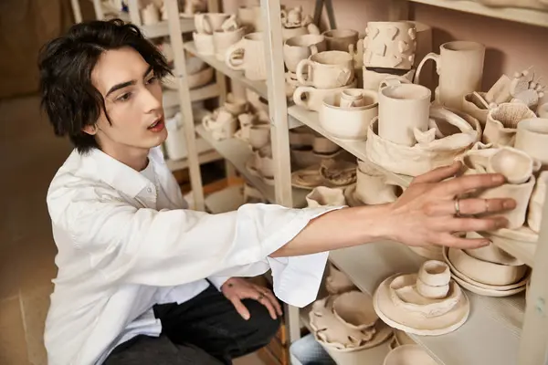 A stylish man discovers unique ceramics in a vibrant pottery studio, highlighting creativity. — Stock Photo