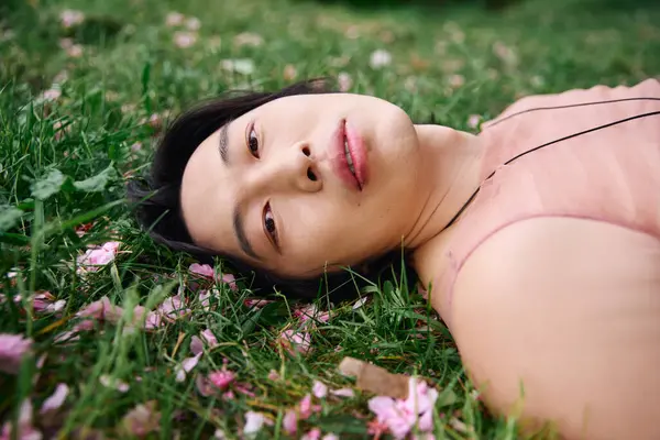 A young Asian man relaxes on the grass, enjoying nature. — Stock Photo