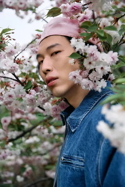 A young man in denim enjoys the serene park surrounded by blooming flowers. — Stock Photo