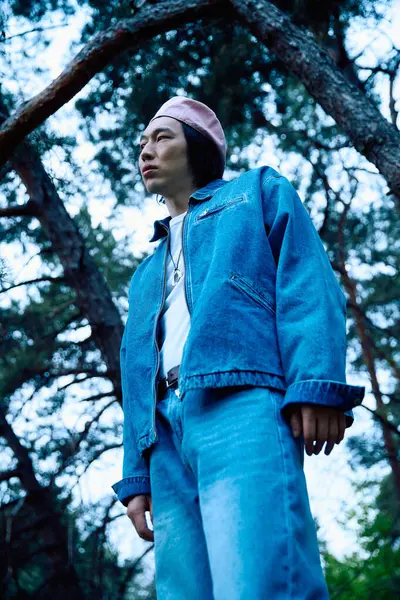 Un jeune homme asiatique modèle une tenue denim tendance dans un beau parc pendant les heures de lumière du jour. — Stock Photo